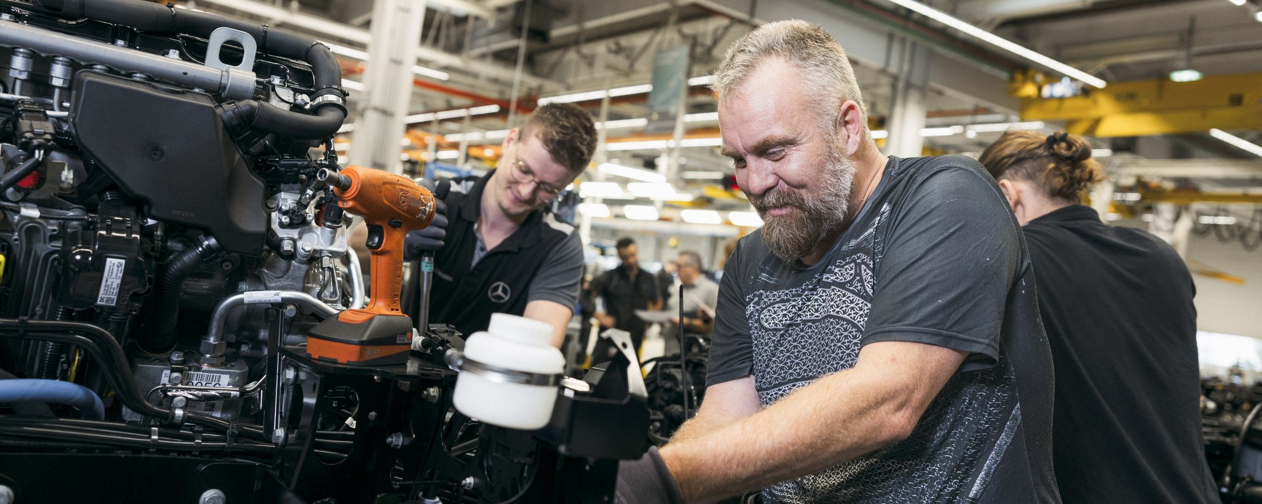 Technische Fachkräfte bei Daimler Truck führen Montagearbeiten an Nutzfahrzeugen in einer modernen Produktionsumgebung durch.