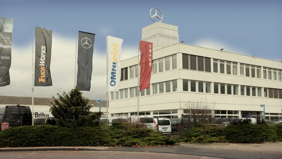 Außenansicht des NFZ-Standorts Koblenz mit TruckWorks-, Omniplus- und Setra-Fahnen vor dem Gebäude.