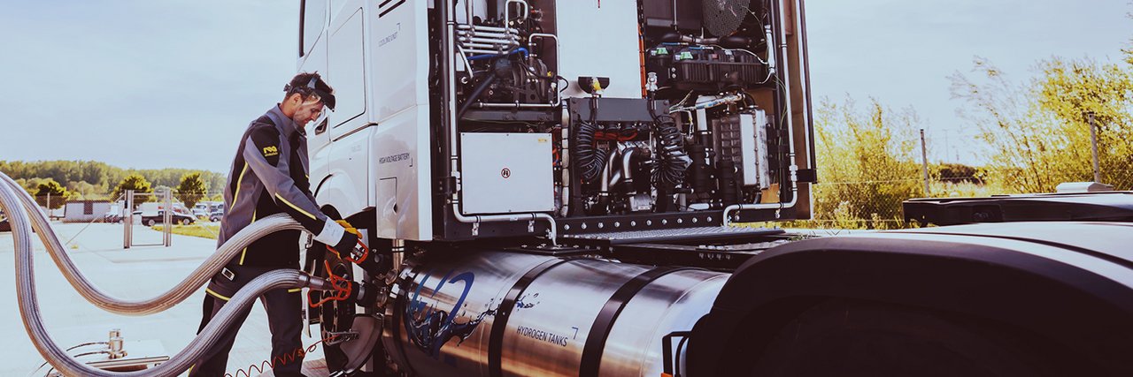 Ein Mitarbeiter betankt den Daimler Truck GenH2 Truck mit Wasserstoff an einer Tankstelle.