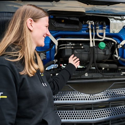 Two participants in the Daimler Truck Leadership Talent Track trainee programme stand in front of an open truck engine and discuss technical details - part of the “Customer First @ First Retail” module.