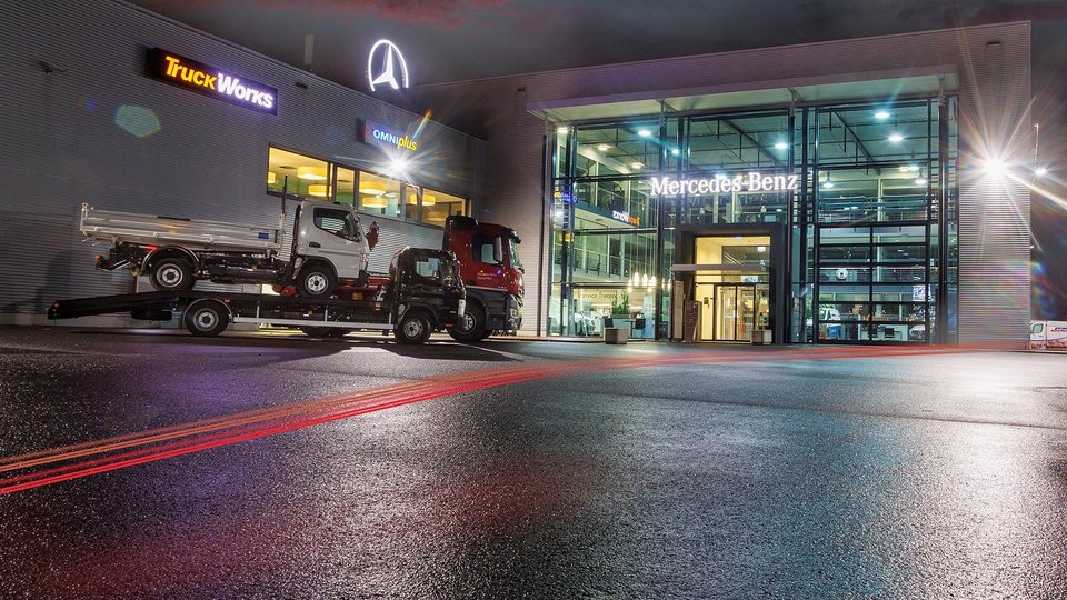Mercedes-Benz Niederlassung in Rhein-Main Kassel – Modernes, beleuchtetes Gebäude bei Nacht mit Glasfassade und Lkw-Transporter im Vordergrund.