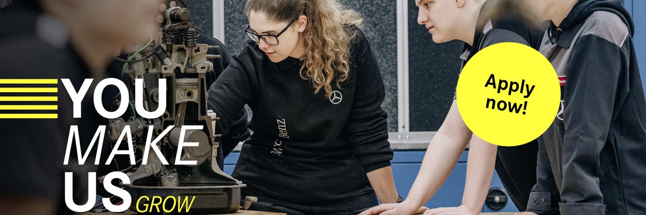 A group of young team members analyse a mechanical device in a workshop. The slogan "You make us grow" can be seen on the left-hand side, accompanied by a yellow button with "Apply now!"