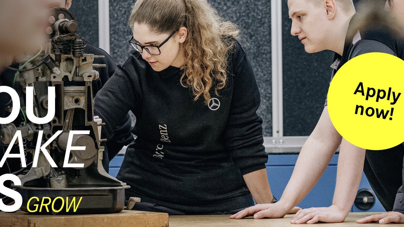 Eine Gruppe von jungen Teammitgliedern analysiert eine mechanische Vorrichtung in einer Werkstatt. Der Slogan 'You make us grow' ist auf der linken Seite zu sehen, begleitet von einem gelben Button mit 'Apply now!'