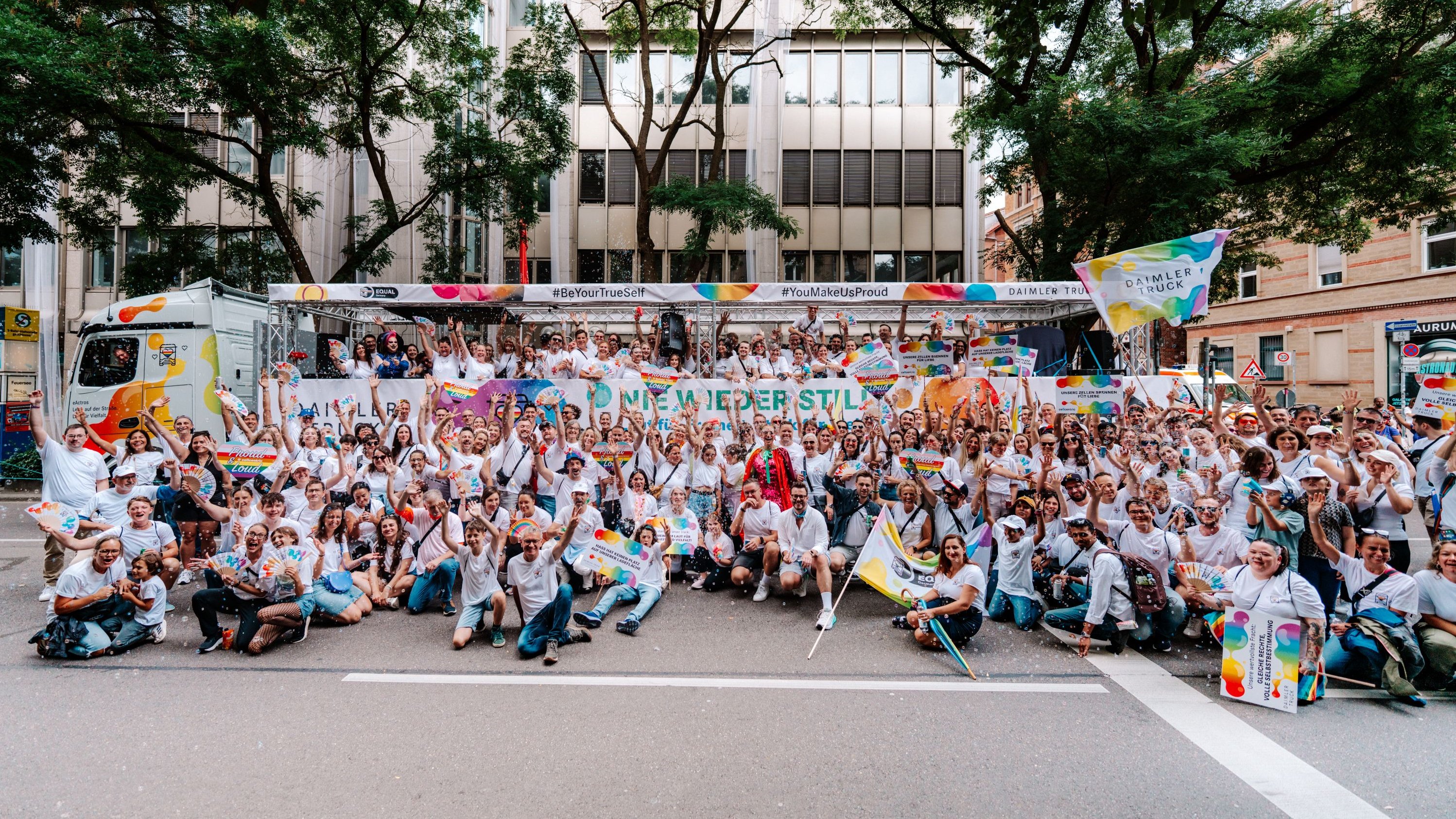 Daimler Truck employees pose in front of the truck at a Pride event.