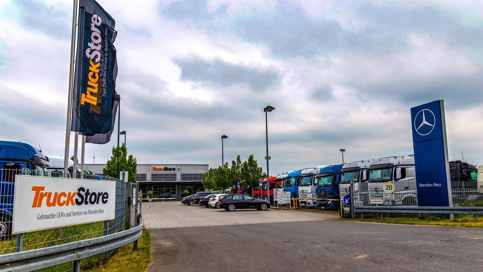TruckStore site in Königs-Wusterhausen with a row of parked lorries and the company building in the background.