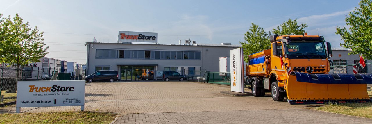 Eingangsbereich des TruckStore Recklinghausen mit einem großen orangen Mercedes-Benz Winterdienstfahrzeug.