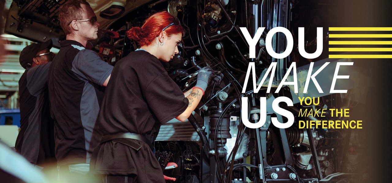 Junge Mitarbeitende montieren Teile an einem Lkw in der Daimler Truck Produktion – Teamarbeit und Einsatz im Ferienjob. Text im Bild: "You make us – You make the difference."