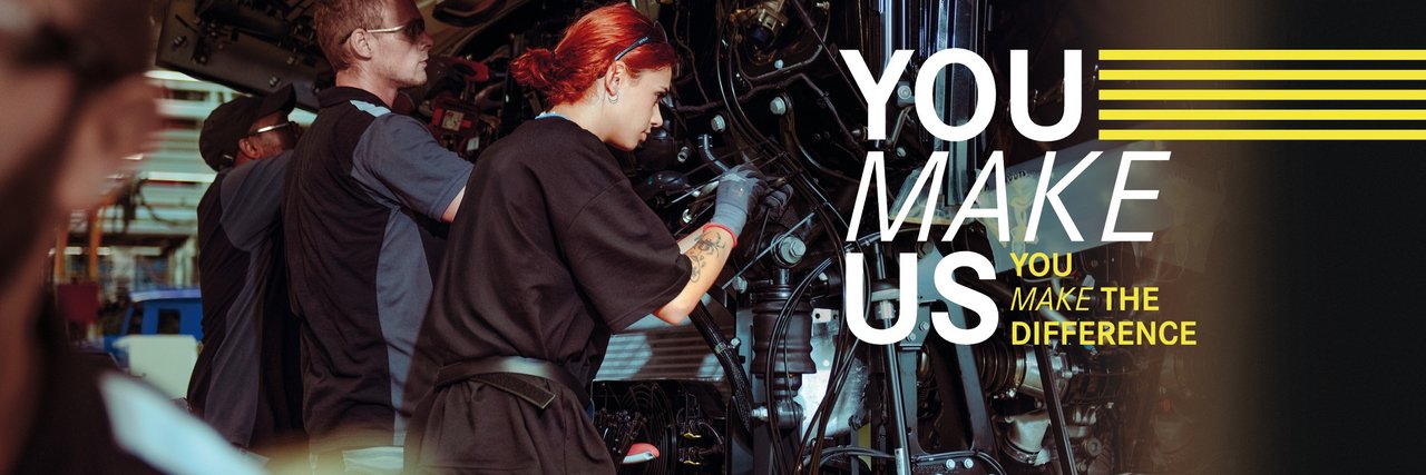 Junge Mitarbeitende montieren Teile an einem Lkw in der Daimler Truck Produktion – Teamarbeit und Einsatz im Ferienjob. Text im Bild: "You make us – You make the difference."