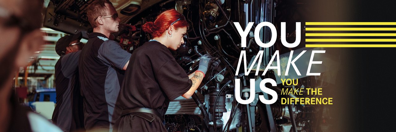 Young employees assemble parts on a truck in Daimler Truck Production - teamwork and commitment in a holiday job. Text in the picture: ‘You make us - You make the difference.’