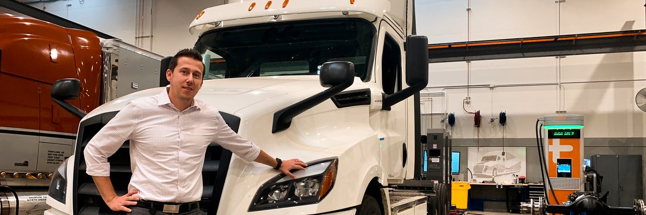 Alexander Voets lehnt sich an einen weißen Freightliner eCascadia in einer Werkshalle.