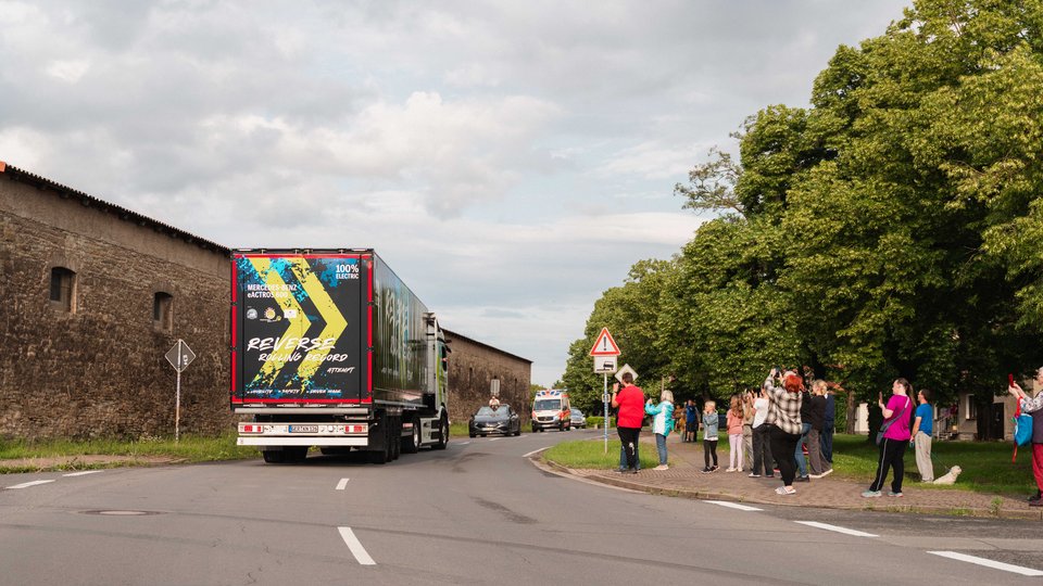 Menschen am Straßenrand bejubeln den rückwärts fahrenden eActros 600.
