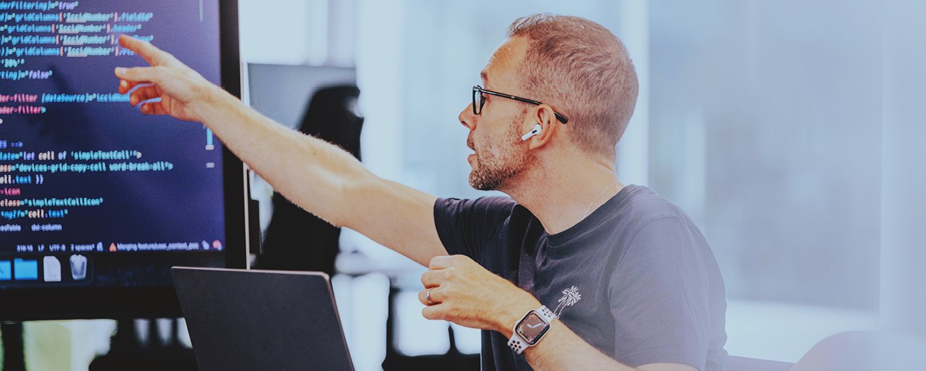 Ein Softwareentwickler zeigt auf Code auf einem Bildschirm während einer Besprechung.