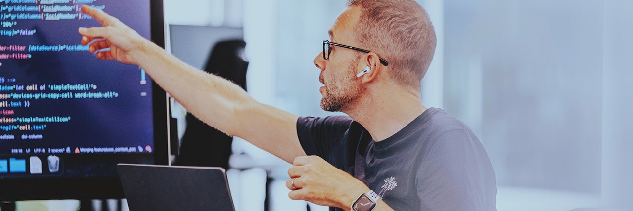 A software developer points to a code on a screen during a meeting.