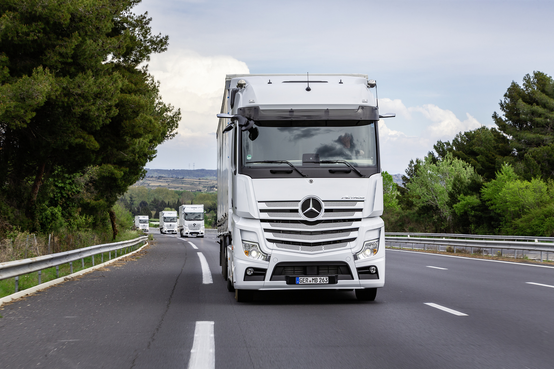 Im Vordergrund: Mercedes-Benz Actros 1853 LS 4x2, Exterieur, arktik-weiß, OM 471 Euro VI mit 390 kW (530 PS), 12,8 L Hubraum, 12-Gang Mercedes PowerShift 3, Active Brake Assist 5, Abstandshalte-Assistent, Verkehrszeichen-Assistent und Abbiege-Assistent, Spurhalte-Assistent, Stabilitätsregel-Assistent, Aufmerksamkeits-Assistent, Active Drive Assist, MirrorCam, Predictive Powertrain Control, BiXenon-Scheinwerfer, L-Fahrerhaus BigSpace Mercedes-Benz Actros mit Active Brake Assist 5 und Abbiege-Assistent, Active Drive Assist, MirrorCam