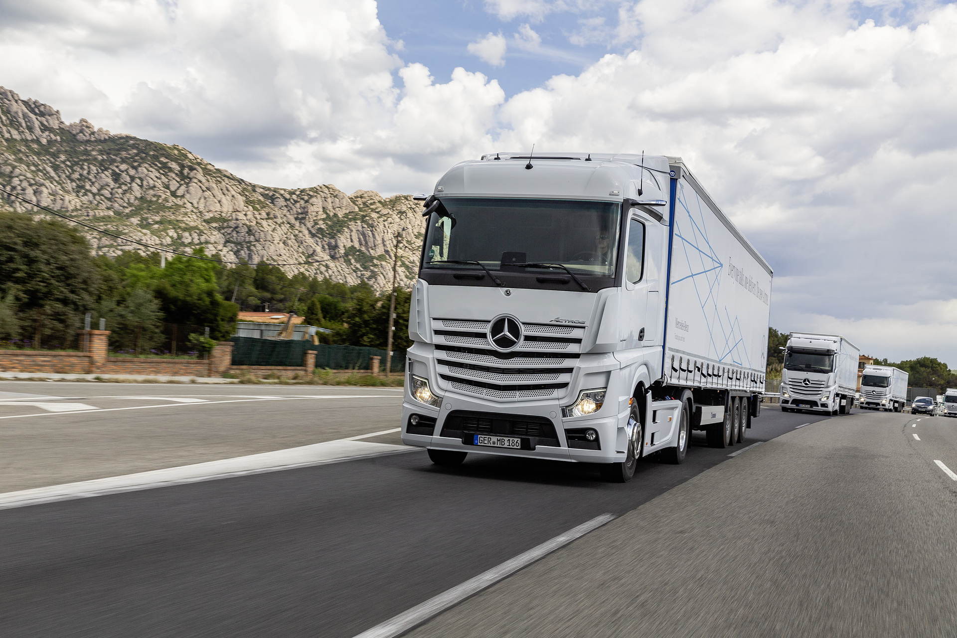 Im Vordergrund: Mercedes-Benz Actros 1845 LS 4x2, Exterieur, arktik-weiß, OM 471 Euro VI mit 330 kW (449 PS), 12,8 L Hubraum, 12-Gang Mercedes PowerShift 3, Active Brake Assist 5, Abstandshalte-Assistent, Verkehrszeichen-Assistent und Abbiege-Assistent, Spurhalte-Assistent, Stabilitätsregel-Assistent, Aufmerksamkeits-Assistent, Active Drive Assist, MirrorCam, Predictive Powertrain Control, L-Fahrerhaus StreamSpace Mercedes-Benz Actros mit Active Brake Assist 5 und Abbiege-Assistent, Active Drive Assist, MirrorCam