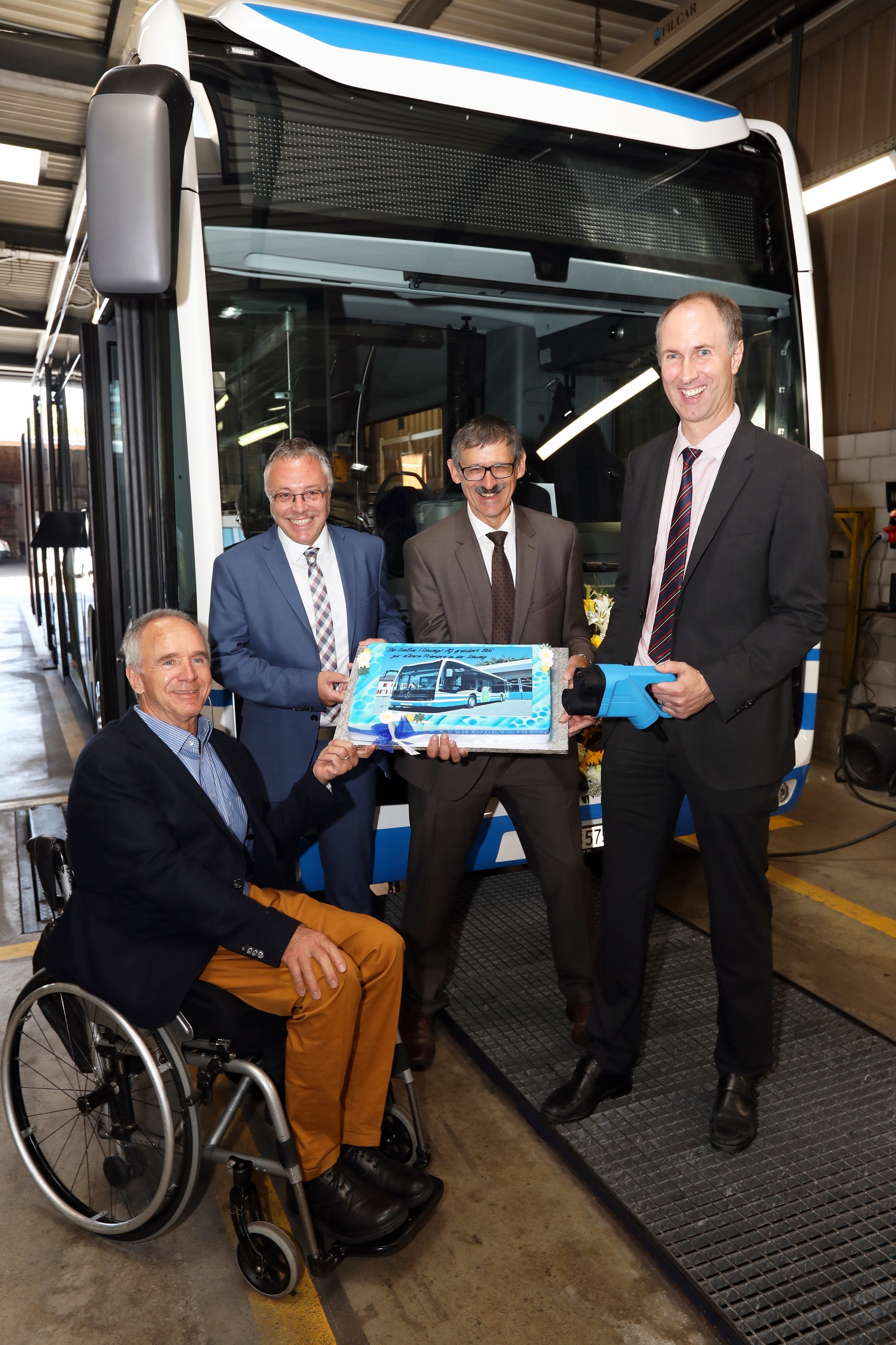 Frank Scherhag, CEO EvoBus (Schweiz) AG (2. von links), und Armin Krieg, EvoBus (Schweiz) AG (2. von rechts), überreichten die Foto-Torte der ersten eCitaro an Hans Frei, Verwaltungsratspräsident BOS (links), und Roland Ochsner, CEO BOS (rechts im Bild).