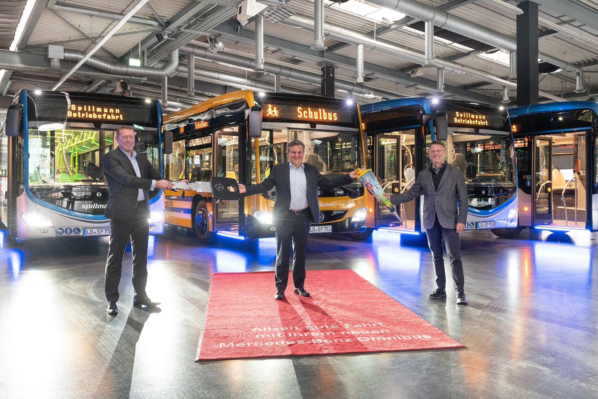 Schluss mit „grauem Einheits-ÖPNV“: Rüdiger Kappel, Leiter Vertrieb Flotten Daimler Buses Deutschland (links), und Herrmann Fröhlich, Leiter Vertriebsregion Südwest Daimler Buses (rechts), übergeben acht außergewöhnlich gestaltete Citaro hybrid an Bülent Menekse, Geschäftsführer der Omnibusverkehr Spillmann GmbH. In Anlehnung an die kommende erste Schulbusfahrt des aufsehenerregend gelb/schwarz lackierten „School Bus“ hat Bülent Menekse eine Schultüte überreicht bekommen. Moderner Nahverkehr beginnt im Omnibus selbst