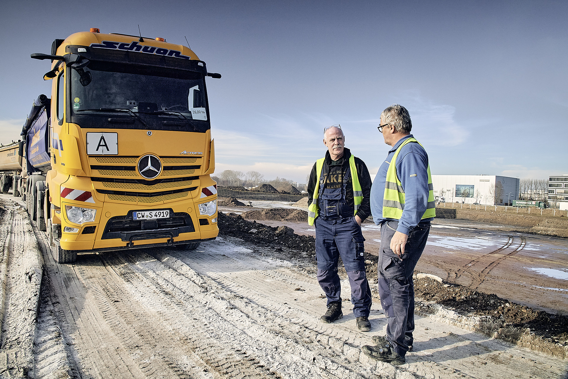 Actros 1846 LS im Transporteinsatz beim Erdaushub der Großbaustelle des Projekts Neubau Flugfeldklinikum in Böblingen. Im Bild zu sehen sind die Fahrer der Spedition Schuon: Dirk Möller (links) und Friedhelm Steinwand (rechts). Starke Kerle transportieren tausende Kubikmeter Erdaushub: Spedition Schuon setzt zwei Mercedes-Benz Actros auf Großbaustelle für Klinik-Neubau in Böblingen-Sindelfingen ein