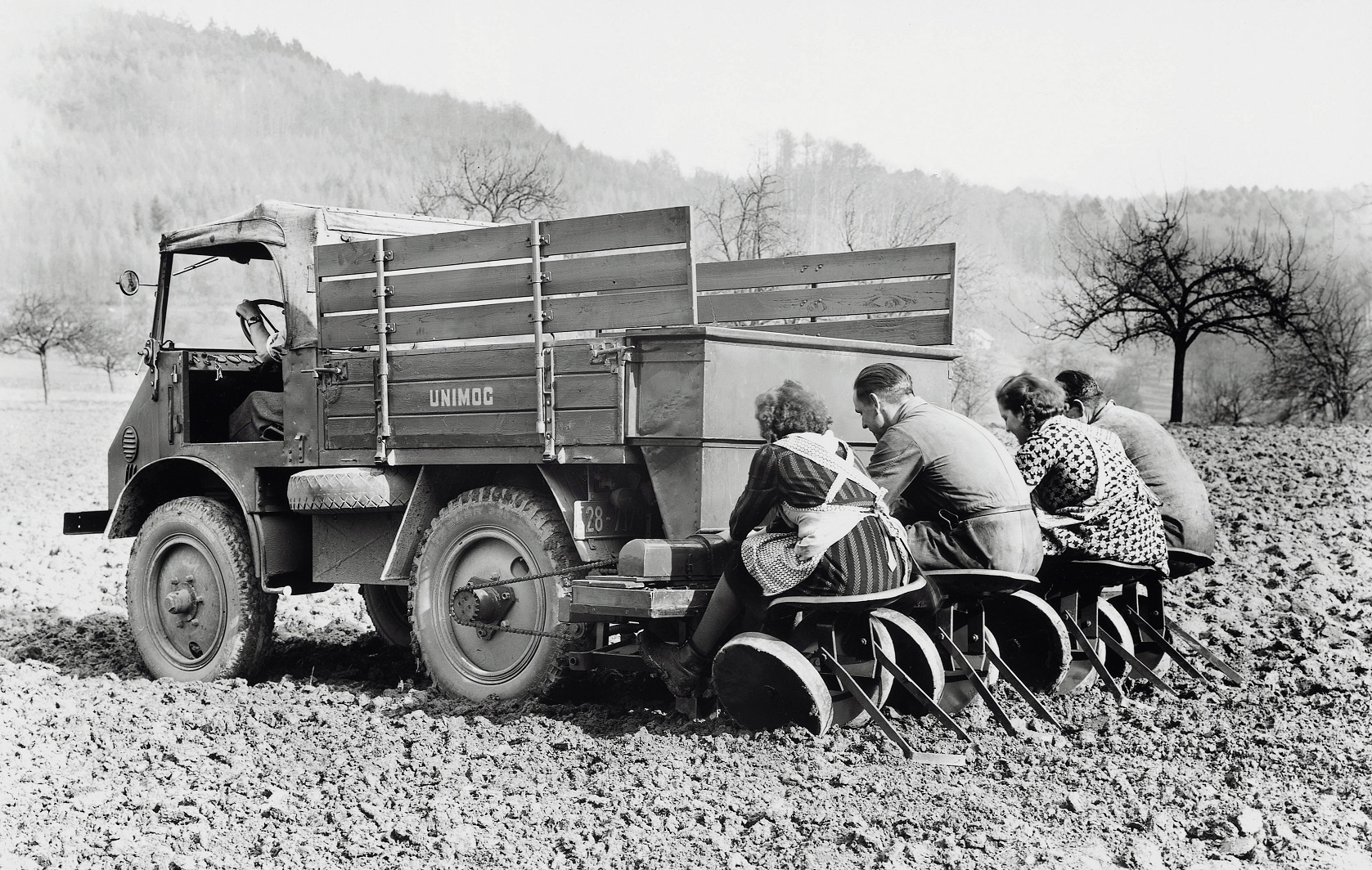 Erntehelfer mit 25 PS: Die halbautomatische Kartoffel-Pflanzmaschine war ein Anbaugerät aus den Anfangsjahren des Unimog. Die Spurbreite des Unimog war auf die Kartoffelreihen ausgelegt: 1270 mm betrug sie und so passten zwei Kartoffelreihen genau zwischen die Räder Unimog – Spurbreite passend für den Kartoffelacker