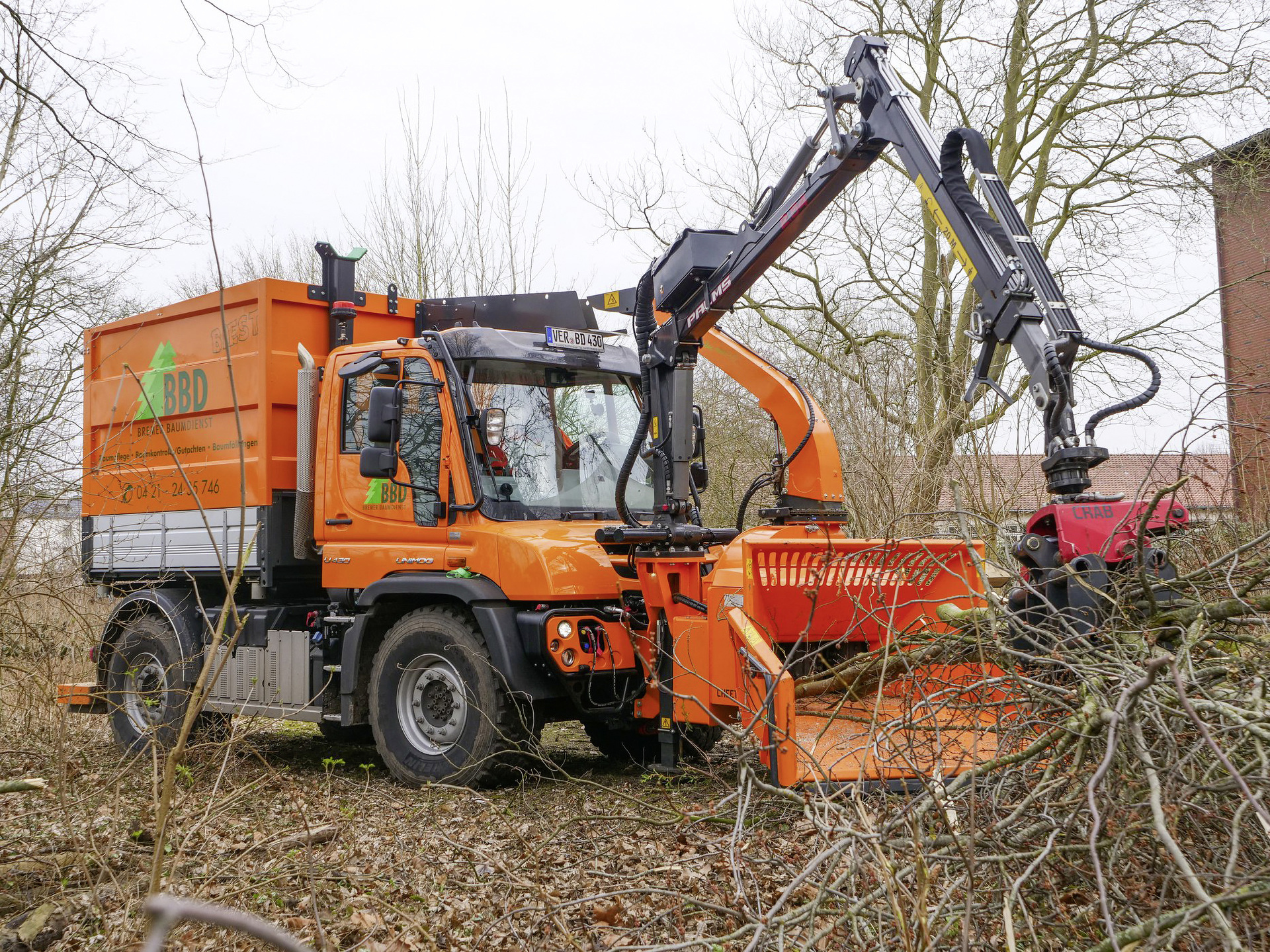 Im Gelände abseits befestigter Wege Bäume fällen, umgestürzte Bäume zerkleinern und die Holzabfälle transportfähig machen: Der orangefarbene Unimog U 430 des Bremer Baumdiensts schafft alle Arbeitsschritte in einem Durchgang. Ausgerüstet ist er mit Kippaufbau, Holzgreifer, Fronthäcksler und - falls nötig - auch einem Teleskopkran. Bäume fällen, Gelände freiräumen: Das „Biest“ erledigt alle Arbeitsschritte in einem Durchgang