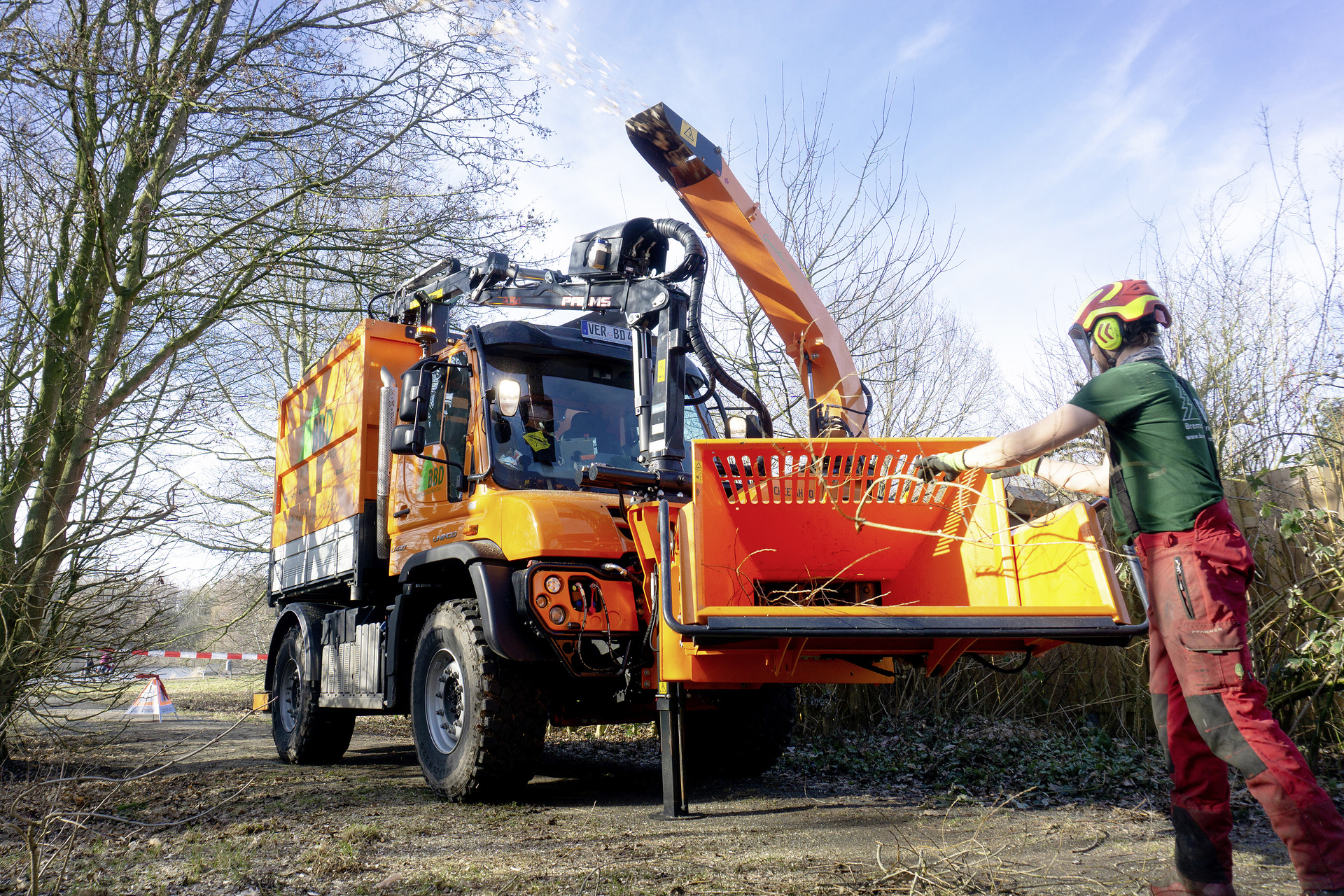 Im Gelände abseits befestigter Wege Bäume fällen, umgestürzte Bäume zerkleinern und die Holzabfälle transportfähig machen: Der orangefarbene Unimog U 430 des Bremer Baumdiensts schafft alle Arbeitsschritte in einem Durchgang. Ausgerüstet ist er mit Kippaufbau, Holzgreifer, Fronthäcksler und - falls nötig - auch einem Teleskopkran. Bäume fällen, Gelände freiräumen: Das „Biest“ erledigt alle Arbeitsschritte in einem Durchgang