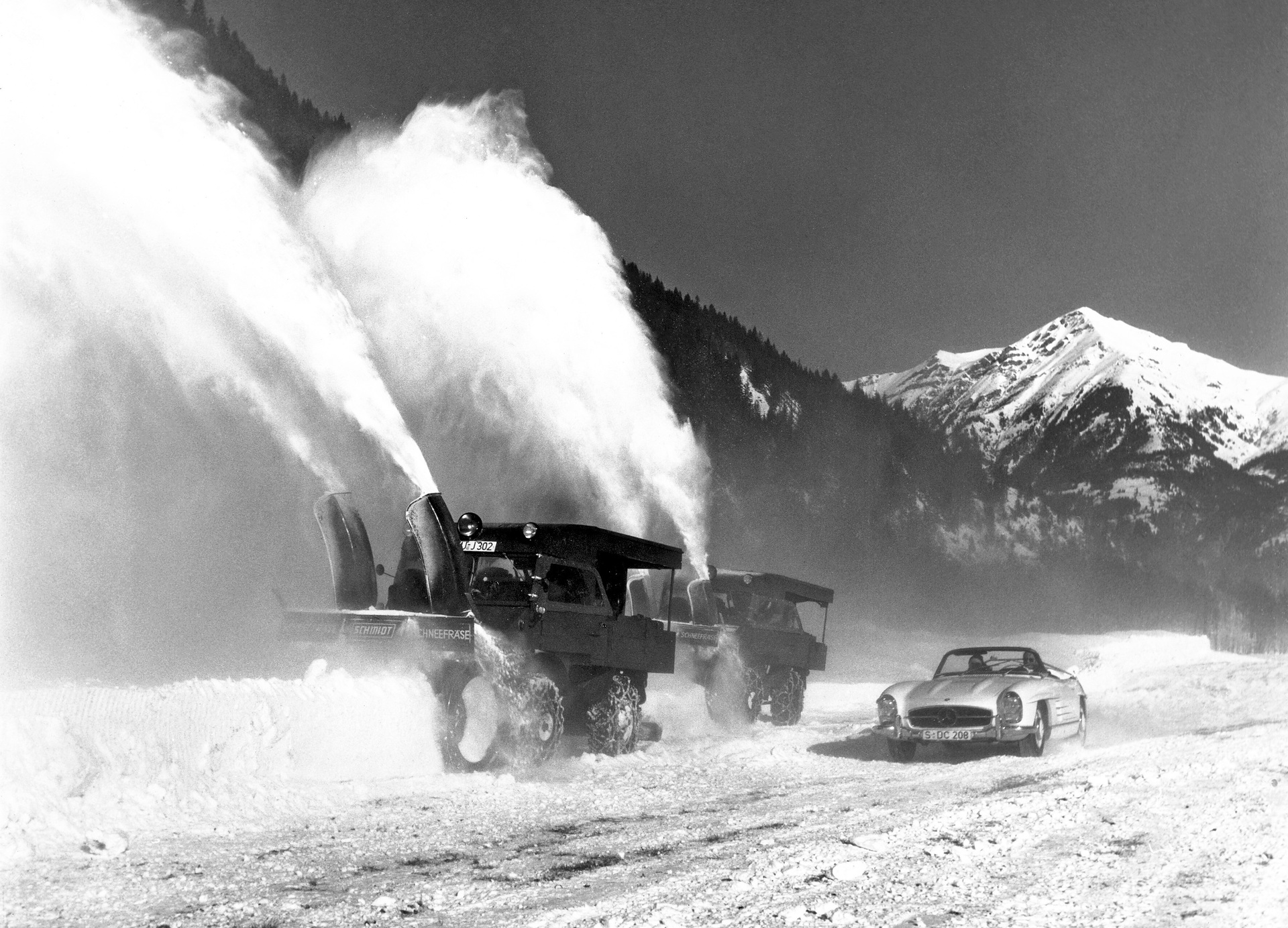 Two Mercedes-Benz Unimogs of the 411 model series with snow blower, powered by an additional engine on the platform. In the foreground, a Mercedes-Benz 300 SL Roadster (W 198). Photo from 1958. (Photo index number in the Mercedes-Benz Classic archives: 58003-82) The universal solution against snow and icy roads: The Unimog U 500 with winter maintenance equipment