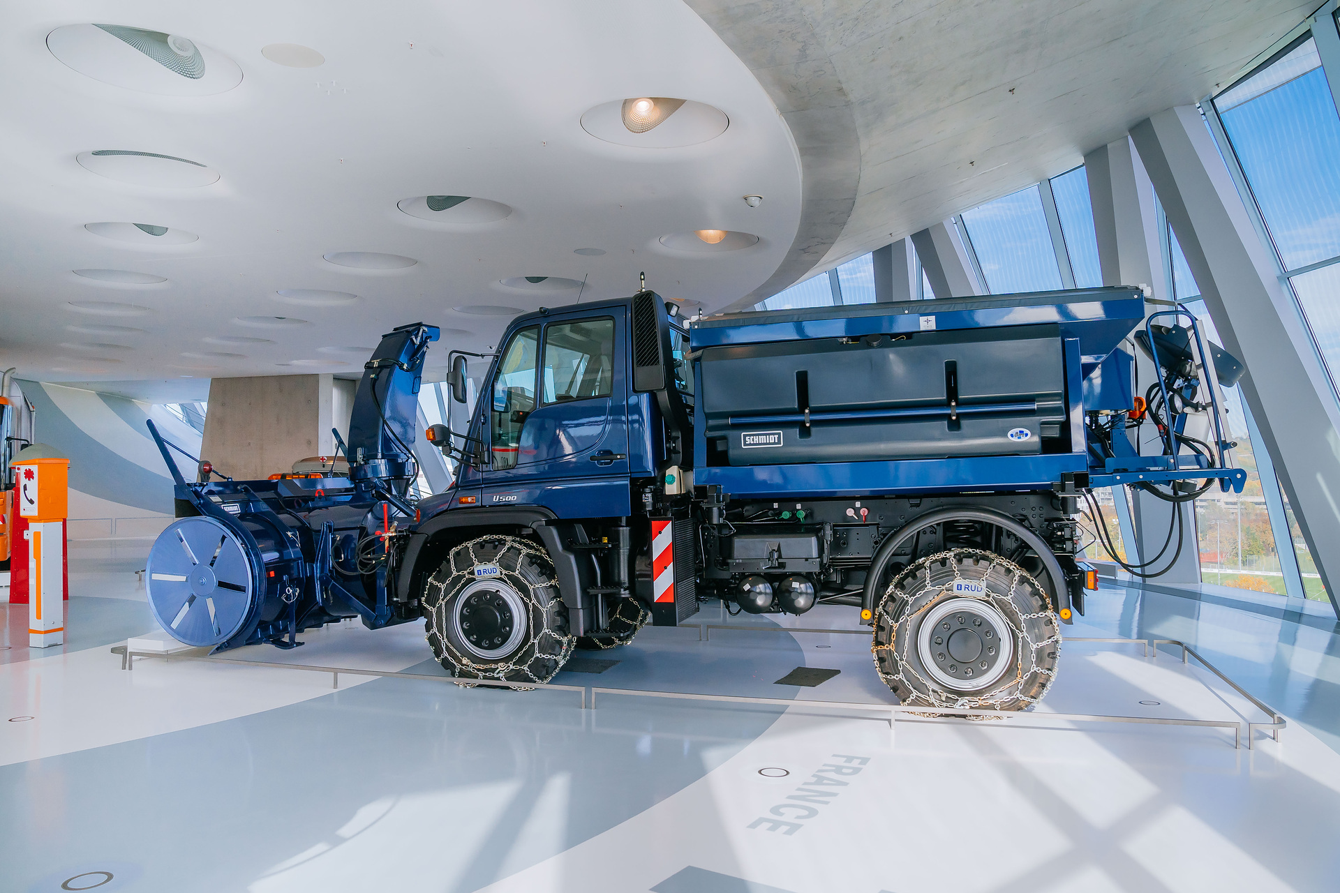 Mercedes-Benz Museum, Collection 3 Room: The Gallery of Helpers. Mercedes-Benz Unimog U 500 of the 405 model series, winter service vehicle with snow blower, snow chains and gritting body from 2004. General view from the left. The universal solution against snow and icy roads: The Unimog U 500 with winter maintenance equipment