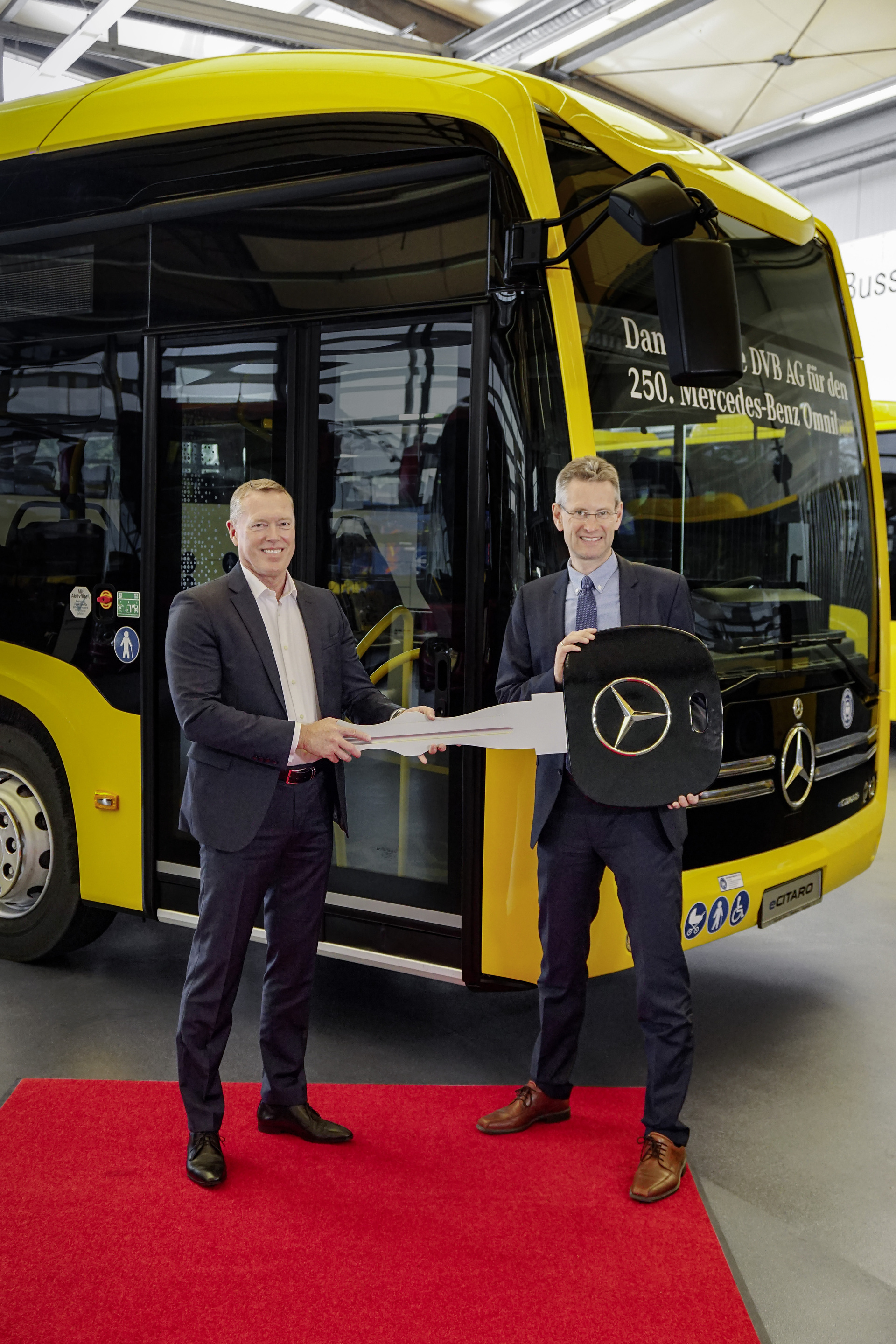 250th bus handover to Dresdner Verkehrsbetriebe AG (DVB). From right: Andreas Hemmersbach (Chief Financial Officer and Technical Officer of DVB, Rüdiger Kappel (Fleet Sales Manager at Daimler Buses Germany), vehicle: Mercedes-Benz eCitaro G with all-electric drive, Dresdner Verkehrsbetriebe AG, exterior, yellow, 4 x electric hub motor (2 x center axle, 2 x rear axle), 4 x 126 kW, 4 x 485 Nm, 5 HV battery packs, 64,5 kWh per HV battery pack, Preventive Brake Assist, Sideguard Assist, length/width/height: 18.125 /2550/3400 mm, passenger capacity: 1/157 Dresden steht unter Strom Verkehrsbetriebe der Landeshauptstadt stellen Buslinie 68 mit Mercedes-Benz eCitaro auf Elektrobetrieb um