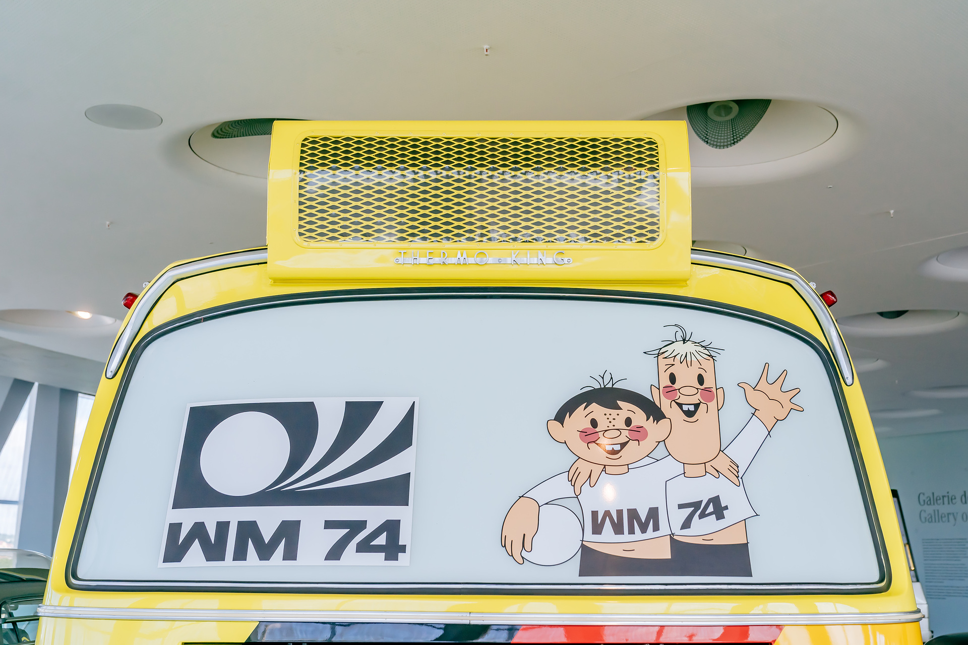 Mercedes-Benz Museum, Raum Collection 4: Galerie der Namen, Reisebus Mercedes-Benz O 302 der westdeutschen Fußballnationalmannschaft während der Weltmeisterschaft von 1974. Rückansicht mit den WM-Maskottchen Tip und Tap. Höchster Buskomfort für die WM-Fußballer 1974