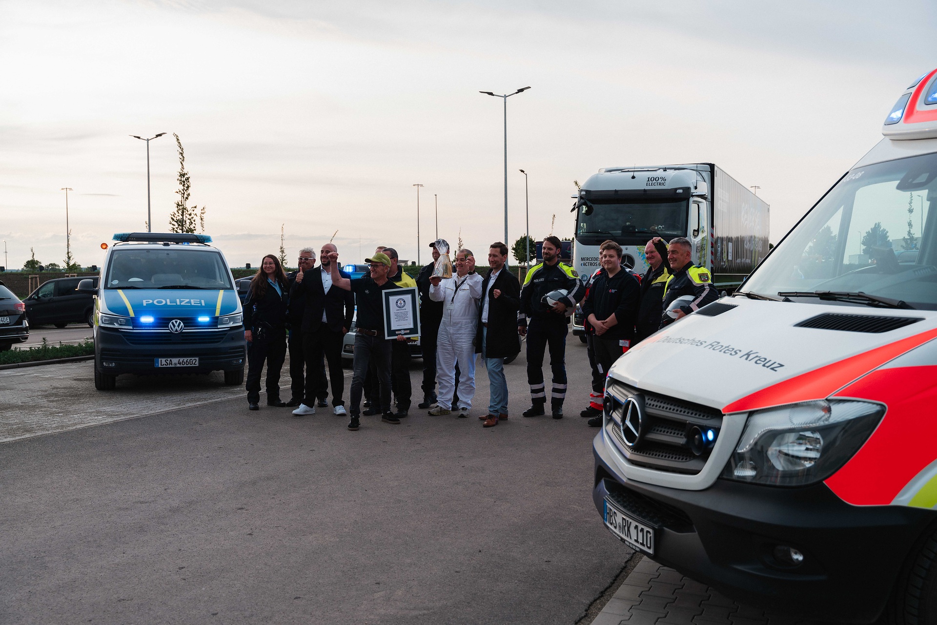 Marco Hellgrewe feiert die erfolgreiche 30 km lange Rückwärtsfahrt nach Halberstadt gemeinsam mit Partnern, darunter die Polizei des Landes Sachsen-Anhalt, das Deutsche Rote Kreuz und Daniel Szarata, Oberbürgermeister der Stadt Halberstadt. Großes Hallo in Halberstadt: eActros 600 fährt 30 Kilometer rückwärts auf öffentlichen Straßen zum Global Parts Center