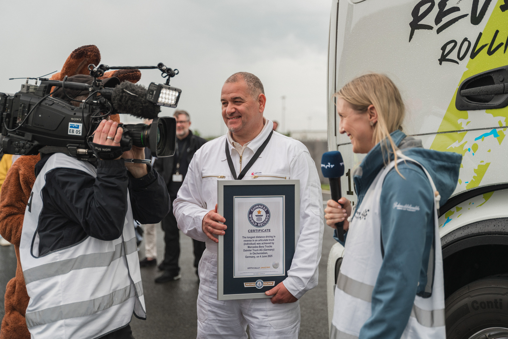 GUINNESS WORLD RECORDS title for the longest distance driven in reverse in an articulated truck (individual). Marco Hellgrewe (center) and Werner Kempfle, Development Engineer and Co-Project Manager of the eActros 600, receive the award from Seyda Subasi-Gemici, Adjudicator, Guinness World Records Limited. Mercedes-Benz Trucks wins GUINNESS WORLD RECORDS™ title with eActros 600