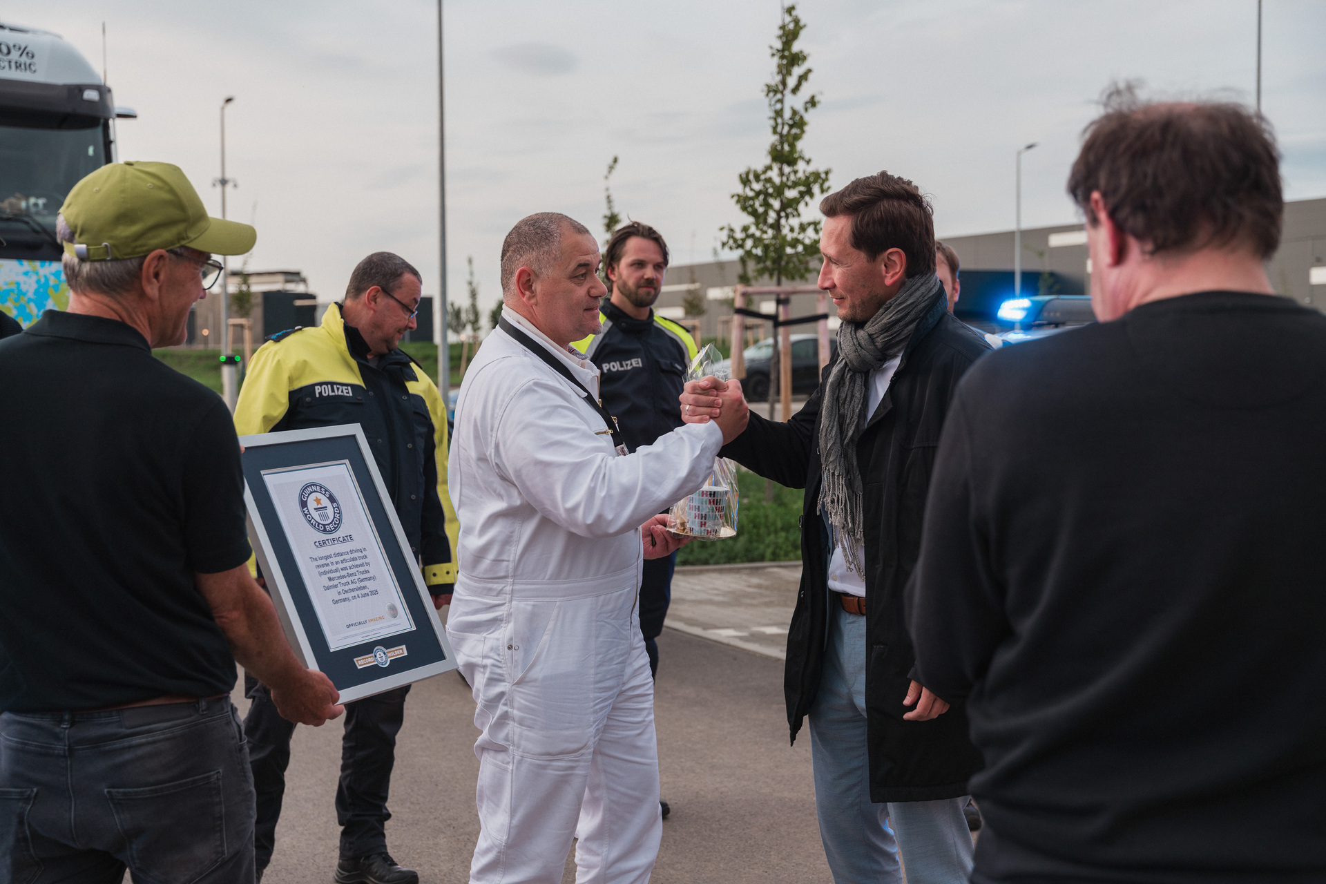 Daniel Szarata, Oberbürgermeister der Stadt Halberstadt (zweiter von rechts), gratuliert Marco Hellgrewe (dritter von links). A big hello in Halberstadt: the eActros 600 reverses 30 kilometers on public roads to the Global Parts Center