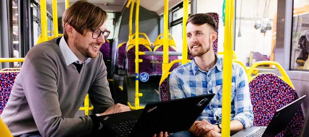Philipp Heyne sits with a colleague in an eCitaro and discusses technical aspects of production on laptops.